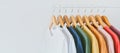 Close up collection of colorful t-shirts hanging on wooden clothes hanger in closet or clothing rack over white background, copy