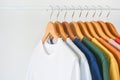 Close up collection of colorful t-shirts hanging on wooden clothes hanger in closet or clothing rack over white background, copy Royalty Free Stock Photo