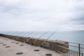 a line of fishing rods near a wall and ocean shore