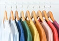 close up collection of pastel color t-shirts hanging on wooden clothes hanger in closet or clothing rack over white background Royalty Free Stock Photo