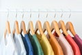 Close up collection of pastel color t-shirts hanging on wooden clothes hanger in closet or clothing rack over white background Royalty Free Stock Photo