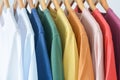 Close up collection of pastel color t-shirts hanging on wooden clothes hanger in closet or clothing rack over white background Royalty Free Stock Photo