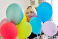 Close up of colored balloons and happy smiling face of blonde teen female Royalty Free Stock Photo