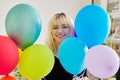 Close up of colored balloons and happy smiling face of blonde teen female Royalty Free Stock Photo