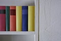 Close up of colorful books in a shelf in white wall