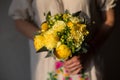 Close up of colorful bouquet in hands of florist in floral print dress.