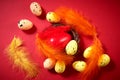 Colorful Easter Eggs with one big red egg in the nest with colored feathers on the red background. Easter greeting