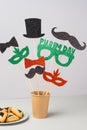 Close up colorful masks, bow, hat, mustached on a stick on a gray background. Happy Purim carnival decoration concept.