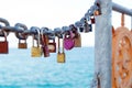 Close up of colorful old rusty love locks on chain on metal railing decorated with a steering wheel against the sea. Selective Royalty Free Stock Photo