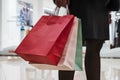 Close up of colorful paper bags in woman's hands on shopping centre background. Woman in skirt and black tights standing in mall Royalty Free Stock Photo