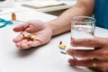 Close up of Colorful pills, capsule medicines and glass of water in man`s hands. Medical and Health care or illness concept Royalty Free Stock Photo
