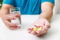 Close up of Colorful pills, capsule medicines and glass of water in man's hands. Medical and Health care or illness concept Royalty Free Stock Photo