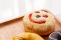 Close up of colorful and sweet donuts and one smiley face donut near windows.