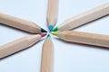 Close-up of a colorful wooden pencils arranged in a symmetrical radial star shape. White background.