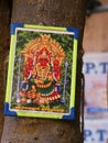 Close up of colourful Hindu poster on tree, Trichy, southern India