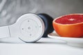 Close up composition of white minimalist headset and half of fresh red grapefruit on a small white plate