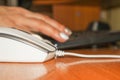 Close-up of a computer mouse and a blurry background in the background - a female hand working on the keyboard. Work Royalty Free Stock Photo