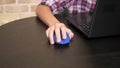 Close-up. Computer mouse in the hand of a teenage boy using a laptop.