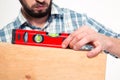 Close up of concenrated bearded young man using spirit level