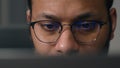 Close up concentrated focused male eyes in eyeglasses looking at laptop monitor screen light reflection in glasses man Royalty Free Stock Photo