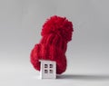 Close up conceptual miniature model house with red wool scarf hat on wooden background Royalty Free Stock Photo