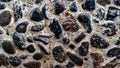 A close-up of a concrete surface embedded with numerous polished, dark pebbles, creating a rough, textured, Royalty Free Stock Photo