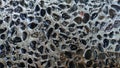 A close-up of a concrete surface embedded with numerous polished, dark pebbles, creating a rough, textured, mosaic-like background Royalty Free Stock Photo