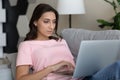 Close up confident Arabian woman using laptop, relaxing on couch