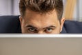 Confident businessman hiding behind laptop computer, looking at camera, spying, peeping Royalty Free Stock Photo