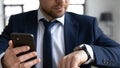 Close up confident businessman holding smartphone, checking time, planning Royalty Free Stock Photo