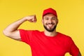 Close-up of confident and cheerful delivery guy showing how storng he is, can carry huge heavy packages, flex piceps and Royalty Free Stock Photo