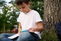 Close-up. Confident portrait of a clever elementary student, handsome intelligent schoolboy doing homework , resting on the public