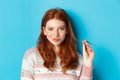 Close-up of confident and sassy redhead teen girl looking at camera pleased, playing with hair strand and smirking