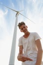 A sassy teenager on a blue sky background. Close-up of stylish hipster guy next to a windmill. Teenage years concept. Royalty Free Stock Photo