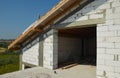 A close-up on the construction of a brick attic with a large window and roofing construction with wooden roof eaves