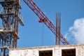 Close-up of a construction crane working against the backdrop of a new building and blue sky, selective focus Royalty Free Stock Photo