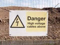 close up construction site fence sign: danger high voltage cables above Royalty Free Stock Photo