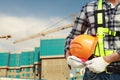 Close up of construction worker carrying safety helmet with crane in the background and building site Royalty Free Stock Photo