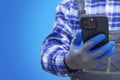 Close-up of a construction worker handyman in protective gloves and workwear using a modern smartphone. Concept digital technology Royalty Free Stock Photo