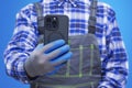 Close-up of a construction worker handyman in protective gloves and workwear using a modern smartphone. Concept digital technology Royalty Free Stock Photo