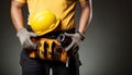 Close-up of a construction worker holding a tool belt and a yellow helmet Royalty Free Stock Photo