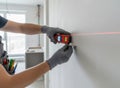 A close-up of a construction worker measuring a white wall with a laser level in a modern apartment undergoing renovation Royalty Free Stock Photo