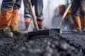 Team of construction workers using shovels to spread asphalt on a road. Close-up street repair scene with focus on tools Royalty Free Stock Photo