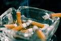 Close up of consumed cigarettes over a crystal ashtray in black background Royalty Free Stock Photo