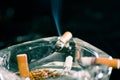 Close up of consumed cigarettes over a crystal ashtray in black background Royalty Free Stock Photo