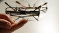 Close-up of a contact lens on a female index finger against the background of glasses on a white table. Royalty Free Stock Photo