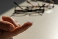 Close-up of a contact lens on a female index finger against the background of glasses on a white table. Royalty Free Stock Photo