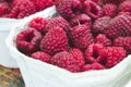 Close-up of a container of fresh, red, ripe raspberries at a food market