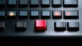 Close-up of a control panel with illuminated buttons featuring a prominent red key among black keys on a brushed metal surface Royalty Free Stock Photo