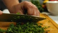 Close-up of a cook chopping a bunch of parsley. Side view. Vegetarian Cuisine. The concept of delicious and healthy food